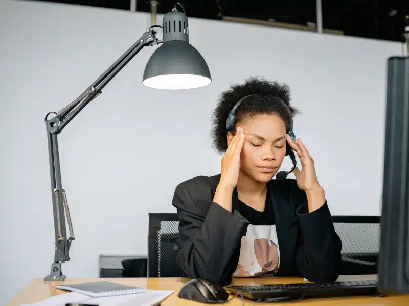 Vrouw aan bureau met vermoeidheids- of spanningsklachten